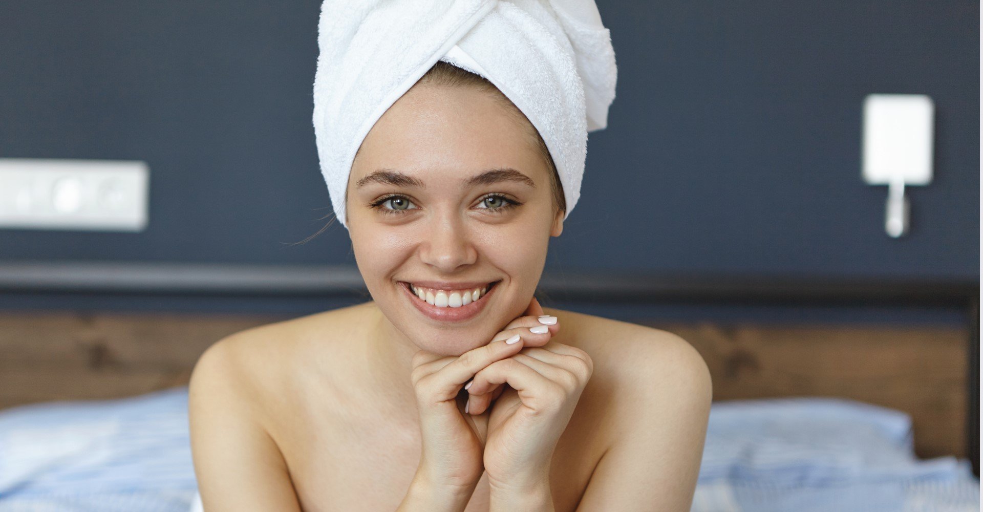 mulher sorri com seus cabelos envolto em uma toalha